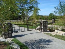Custom gate pillar box design encasing stones with rustic and sturdy steel gate. 